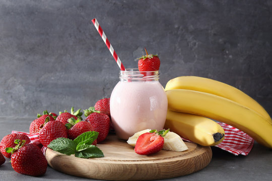 Jar of delicious strawberry and banana homemade smoothie on cutting board