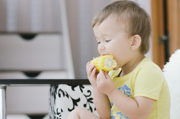 child in a yellow shirt eating corn