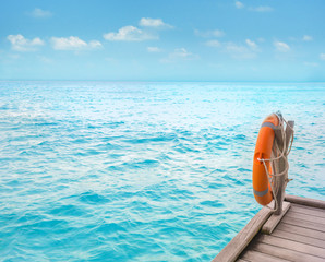 Fototapeta na wymiar Wooden pontoon with flotation ring at sea resort in summer day