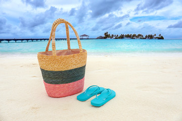 Bag and flip-flops on sea beach. Summer vacation concept