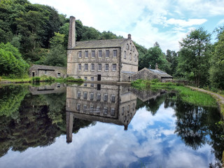 gibson mill a water powered mill with main bulding relected in the pond and surroounding trees of hardcastle crags near hebden bridge in west yorkshire