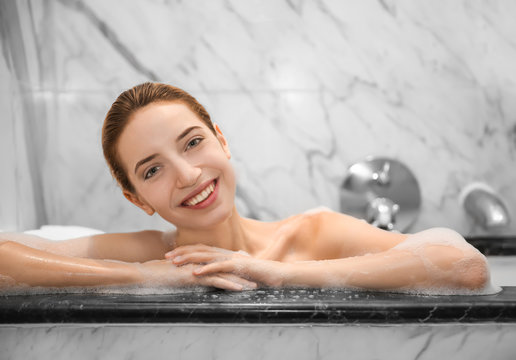Woman relaxing in bath with foam. Spa treatment concept