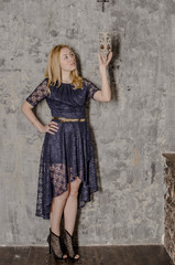 Beautiful blond woman in a dress standing by an old wall
