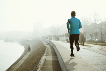 Runner exercising outdoor in fog and misty weather to stay activ