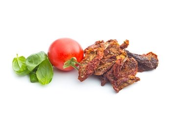 Dried sliced tomatoes and fresh tomatoes with basil leaves.