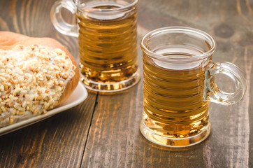 two glasses with tea and croissant/two glasses with tea and croissant on a wooden background