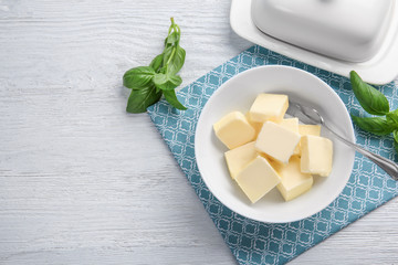 Bowl with cubes of butter and greens on light table