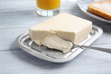 Piece of butter in dish on wooden table