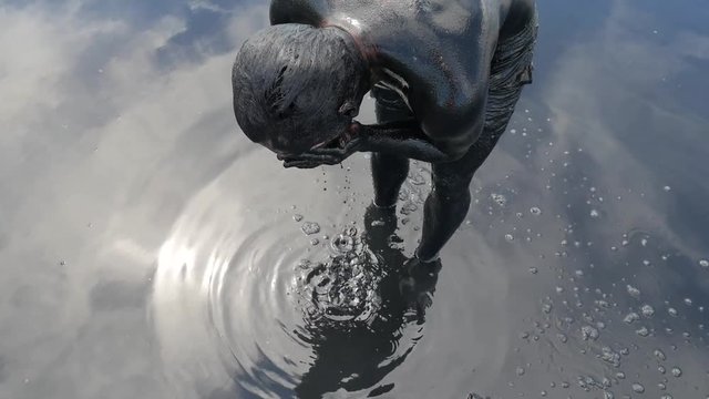 Young Tourist Bather Man Covered with Black Medical Mud at the Lake of Salt Water. Salty Black Dirt Is Good For People With Health and Skin Problems. HD Slowmotion.