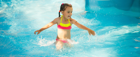 Swimming pool slides for children on water slide at aquapark . Summer kid holiday outdoor. Little girl in aqua park.