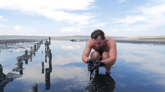 Tourist Sitting in Black Medical Mud Pond with Salty Water. HD Slowmotion.