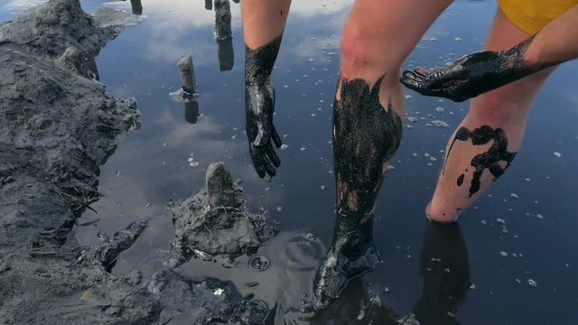Young Man Making Body Healthy Skin Mask with Black Medical Mud at the Lake of Salty Water. HD Slowmotion.