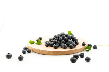Blueberries on a wooden plate on a white