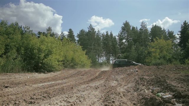 The car rides along the sandy road in the forest