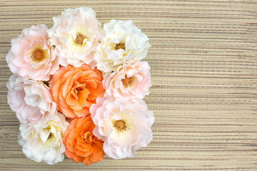 Pink and orange roses on a straw napkin