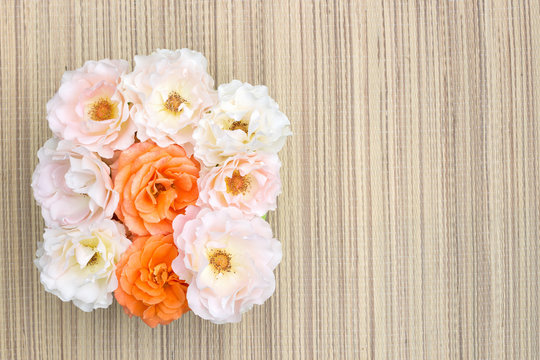 Pink and orange roses on a straw napkin