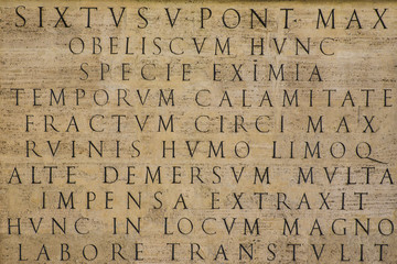 Dettaglio di un'iscrizione in latino e risalente agli antichi romani, ora su un obelisco situato a Roma. La base è di marmo e la scrittura traiana. - obrazy, fototapety, plakaty