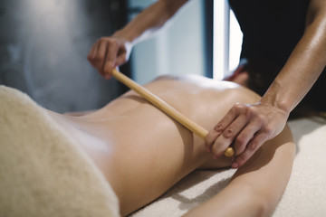 Obraz na płótnie Canvas Masseur using massage bamboo sticks