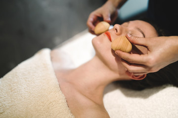 Obraz na płótnie Canvas Masseur massaging face with heated objects