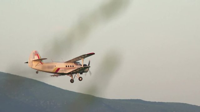 A crop duster applies chemicals to a field 