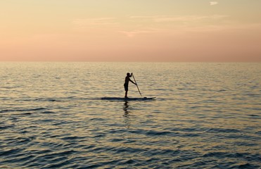 Fototapeta na wymiar Solitary man SUP stand up paddle boarding