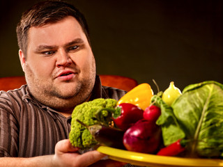 Diet fat man eating healthy food with vegetables for overweight male. Male trying to lose weight first time .Hungry person ready to eat everything. He is trying to go on a diet.