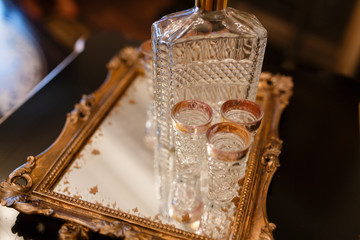 Glass stack and a crystal decanter on a tray with gold trim.
