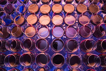 A lot of glasses with alcohol, white wine glasses crossing red wine glass. Wine bottle pouring a row of glasses for tasting for service in night party and event. wineglass with wine close-up