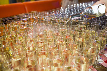 A lot of glasses with alcohol, white wine glasses crossing red wine glass. Wine bottle pouring a row of glasses for tasting for service in night party and event. wineglass with wine close-up