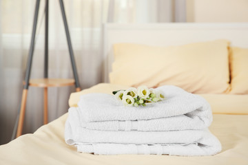 Stack of towels and flowers on bed in hotel room