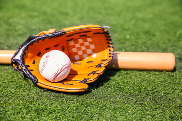 Baseball ball, glove and bat on fresh green grass outdoors