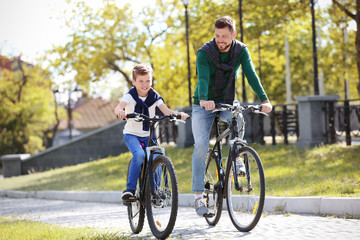 Obraz premium Dad and son riding bicycles outdoors