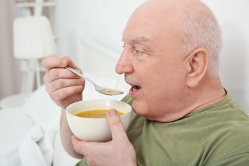 Elderly man eating soup in bed