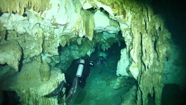 Scuba divers swim in Cenote Dos Ojos cave system