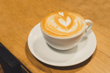 Latte art coffee in wooden table.