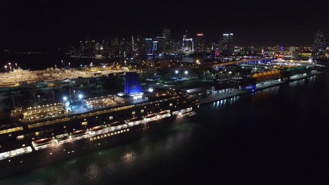 Aerial view of the Port of Miami at night with the city skyline in the background.