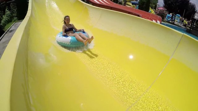 Girl rides a yellow slide in aquapark, falling 
