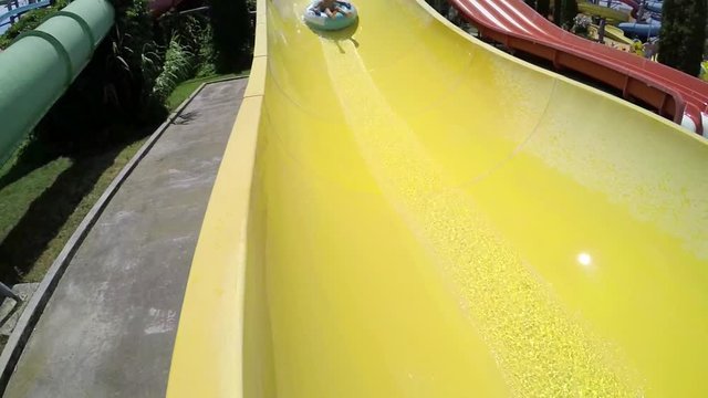 Boy rides a yellow slide in aquapark, falling 
