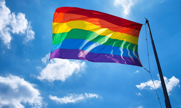 Rainbow flag on cloudy sky symbol of tolerance and acceptance