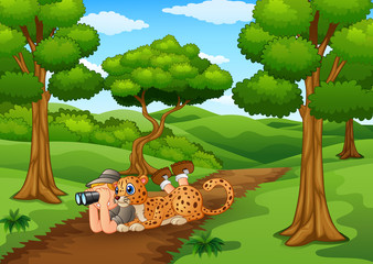 Zookeeper boy with binoculars and leopard in the jungle