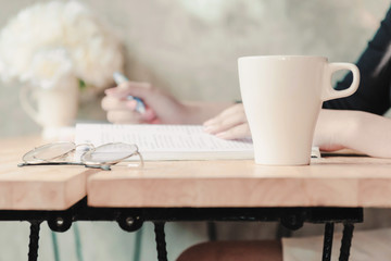 Coffee mug is on the reading table in the library.