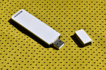 A modern portable USB wi-fi adapter is placed on the yellow sportswear made of polyester nylon fiber