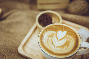 coffee latte art served on wood plate decorated in cafe brown color tone vintage style.