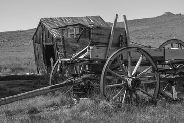 Fototapeta na wymiar Old Wagon and Barn in Black and White, in the old mining town of Bodie State Park