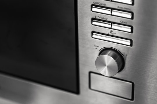 closeup clean new kitchen microwave cooker knob heat volume switch elegant metal steel black and white.