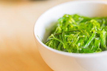 seaweed salad. Japanese healthy food from sea served in bowl on wood table with space for text.