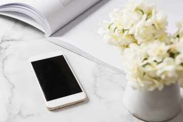 Cell phone device on a white marble bench with flowers