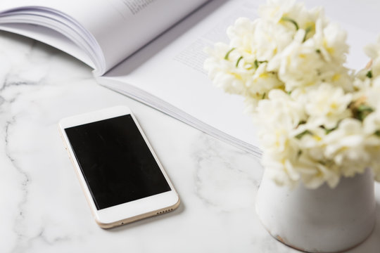 Cell Phone Device On A White Marble Bench With Flowers