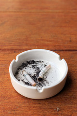 closeup white ashtray on wooden with over light in the background