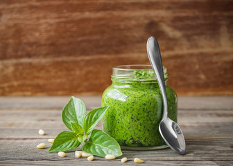 Traditional pesto sauce in a glass jar on the kitchen table